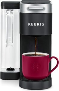  A sleek black coffee maker with a digital display, featuring a water reservoir on the left side and a pod chamber on the top. A coffee cup is placed beneath the dispenser."