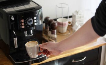 "Keurig coffee maker: Sleek black model with illuminated buttons and a clear water reservoir on the side."