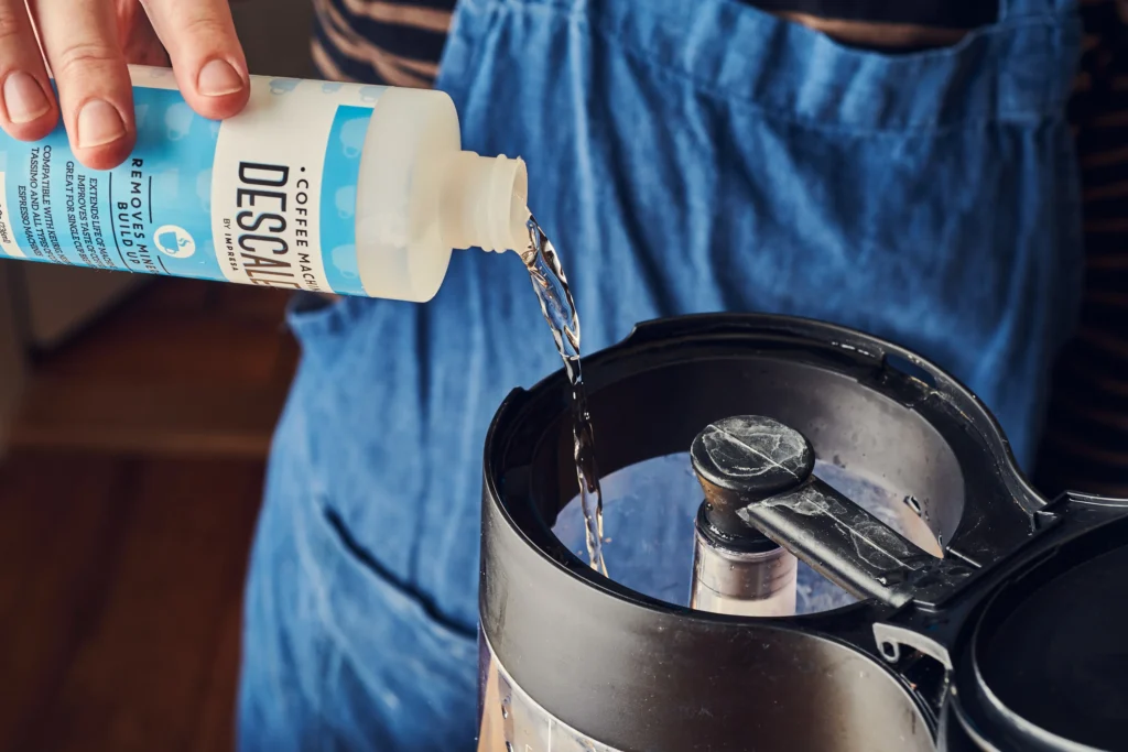 Pouring vinegar solution to clean thermal coffee carafe