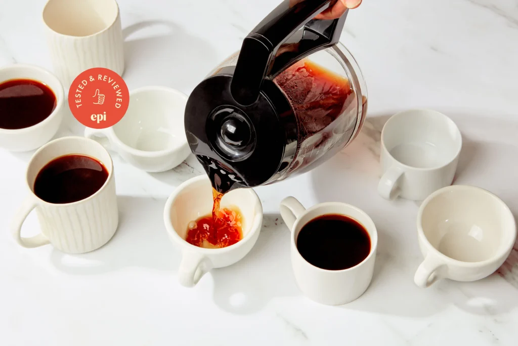 A glass carafe filled with freshly brewed coffee next to a coffee mug.