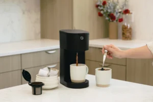 Modern single-serve drip coffee maker with hot coffee in a white mug
