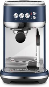 "A compact espresso machine in Damson Blue by Breville, known as the Bambino Plus. It features an automatic milk frother, fast heat-up time, and preset espresso shot buttons for convenient espresso brewing."