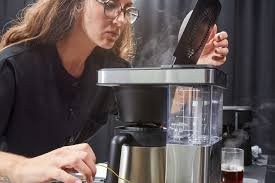 Someone pressing the programmable clock button on a coffee maker.