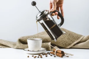 Image of man filling a cup with  a french press coffee maker.