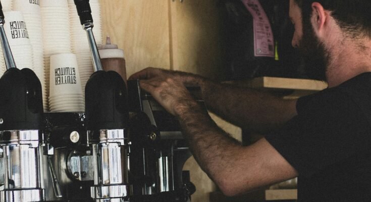 Image of a man standing close to the coffee maker.