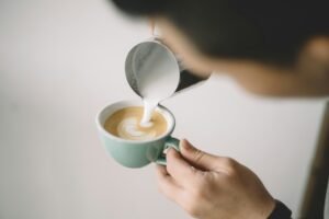 Image of a man filling cup with espresso with a coffe up on the othr hand.