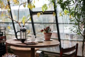 Image of a cafe containing a table and a  cup of carafe placed on it.