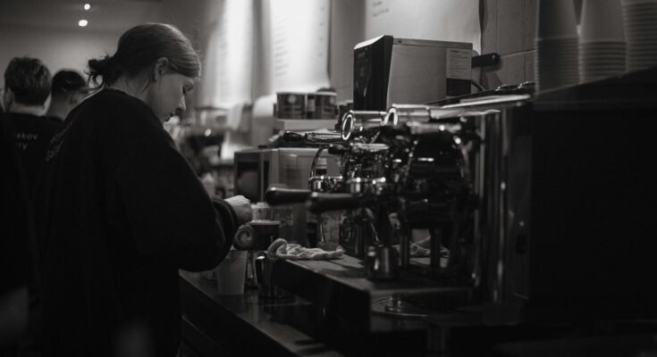 A woman standing closeto coffee maker inpecting it.