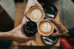 Image of a three cups carried by 3 people having espresso in them.